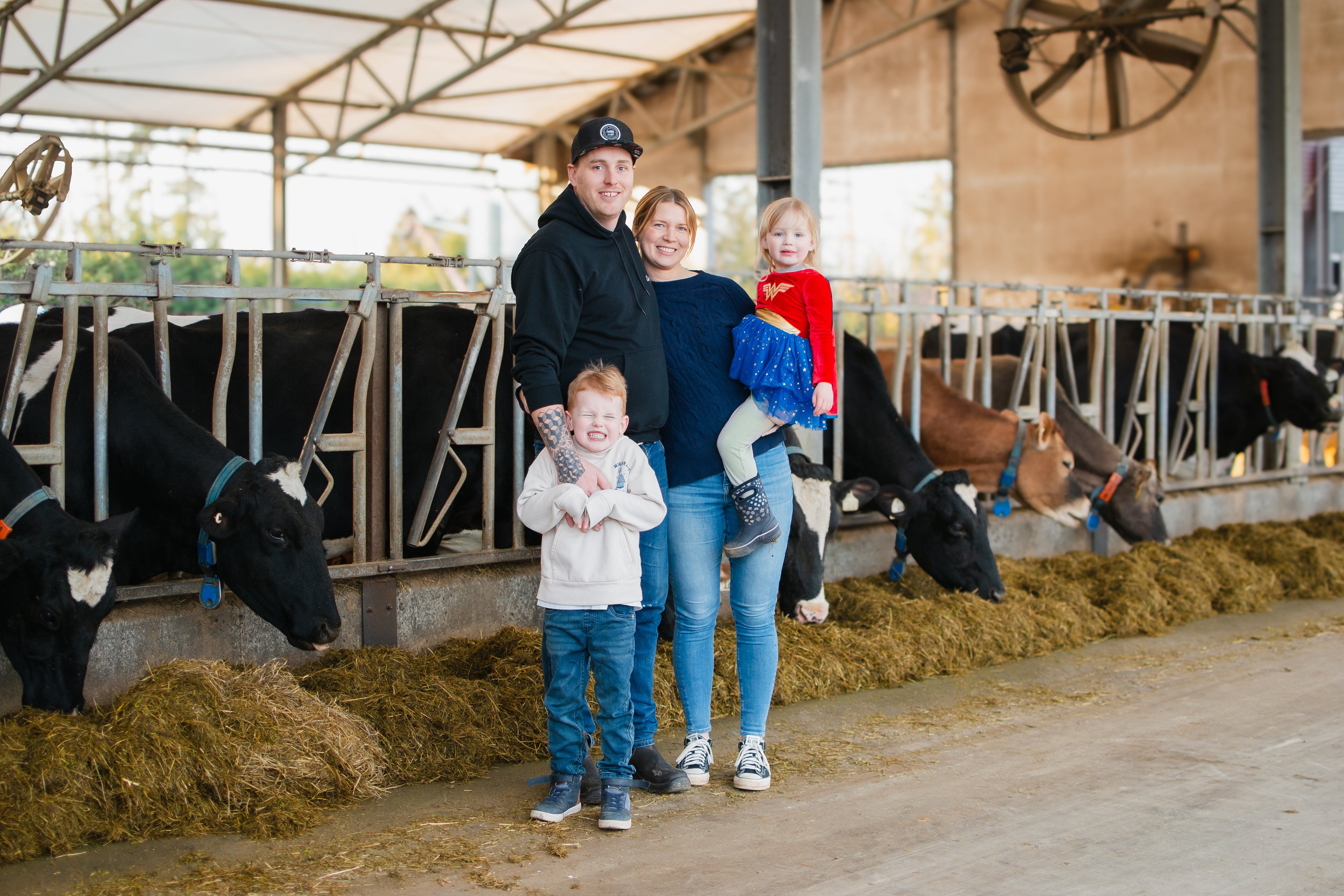 Chelsea and Albert with family in cow barn with cows eating