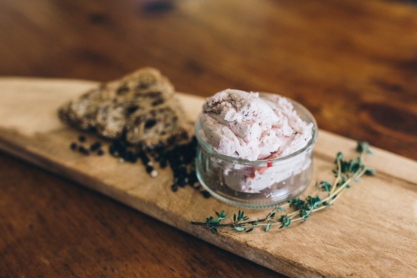Fromage Frais Cranberry Pepper is shown in a serving jar next to peppercorns and bread.