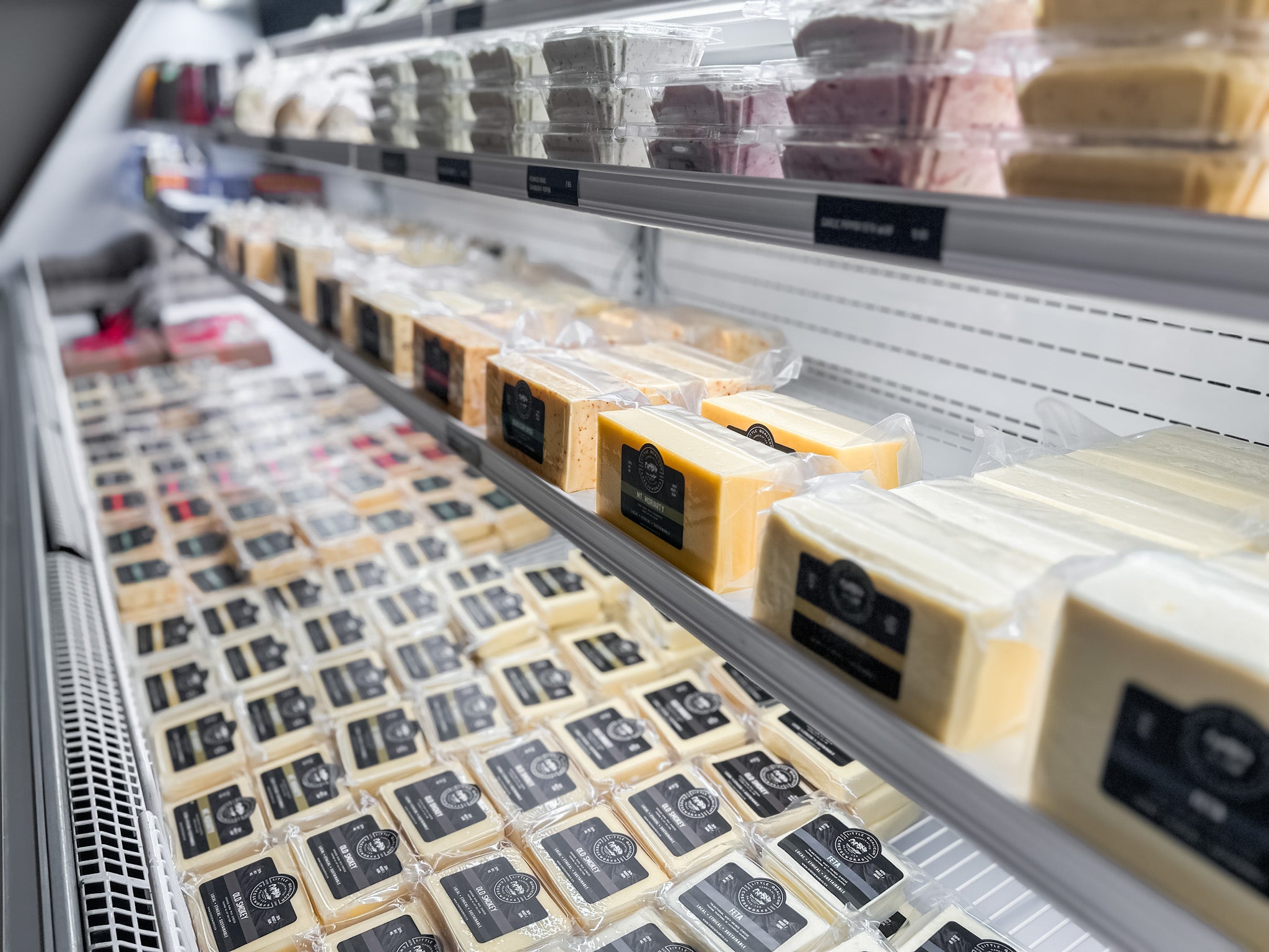 Packaged cheese is displayed in a cooler