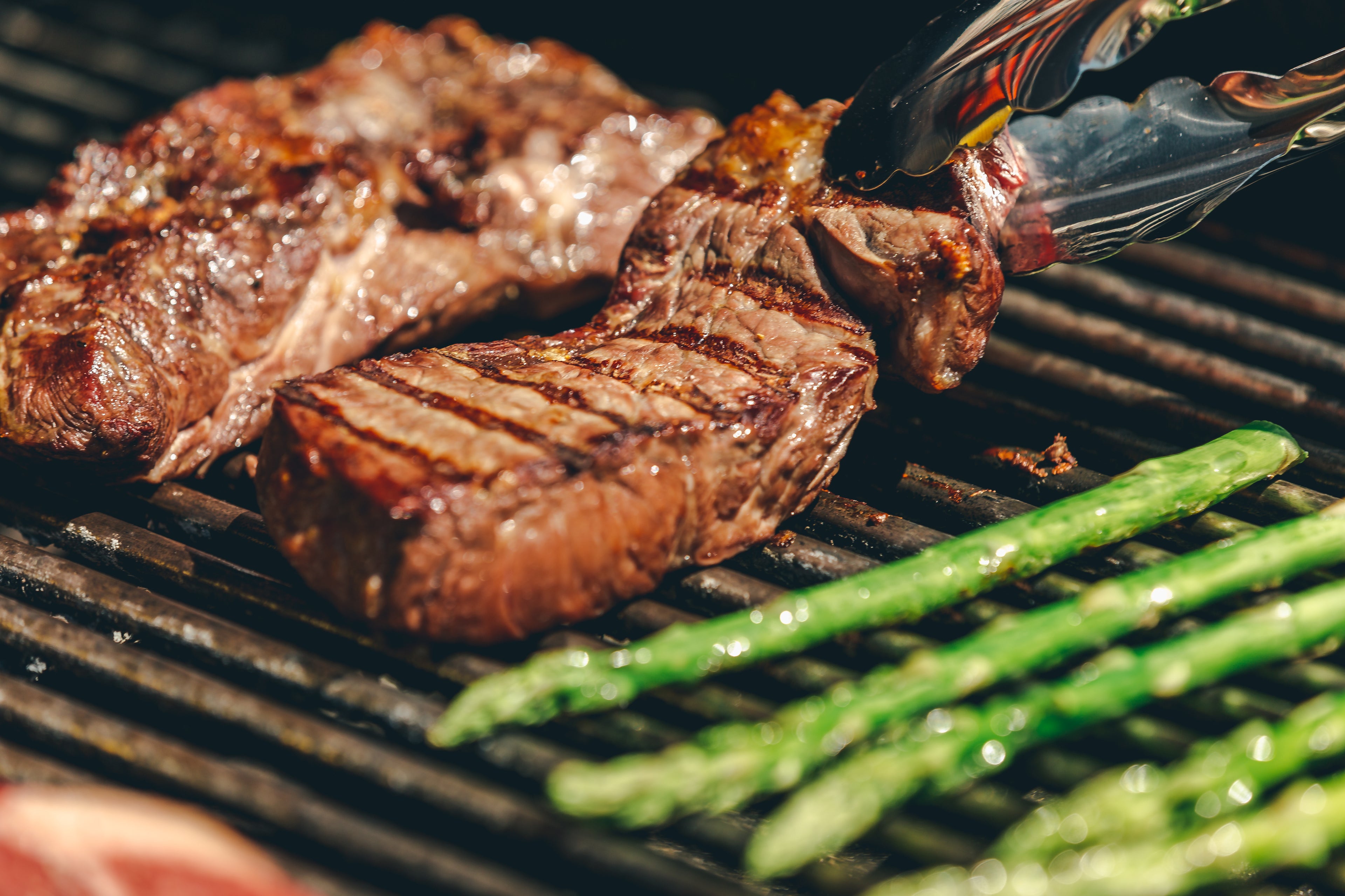 A steak on a grill right after being flipped.