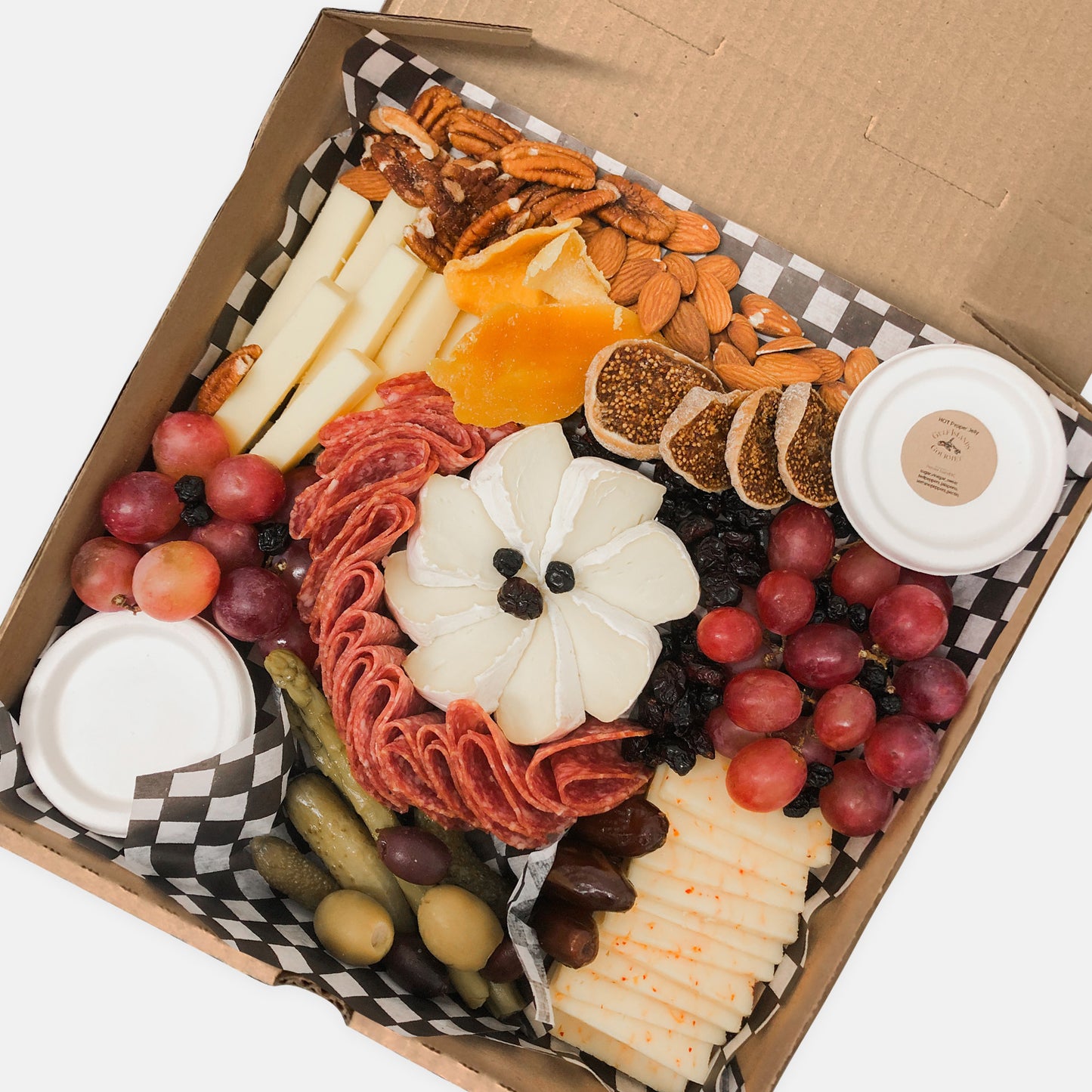 Small grazer box with cheese, meat, nuts, fruit, figs, pickled vegetables, olives, dates and jelly in a pizza box