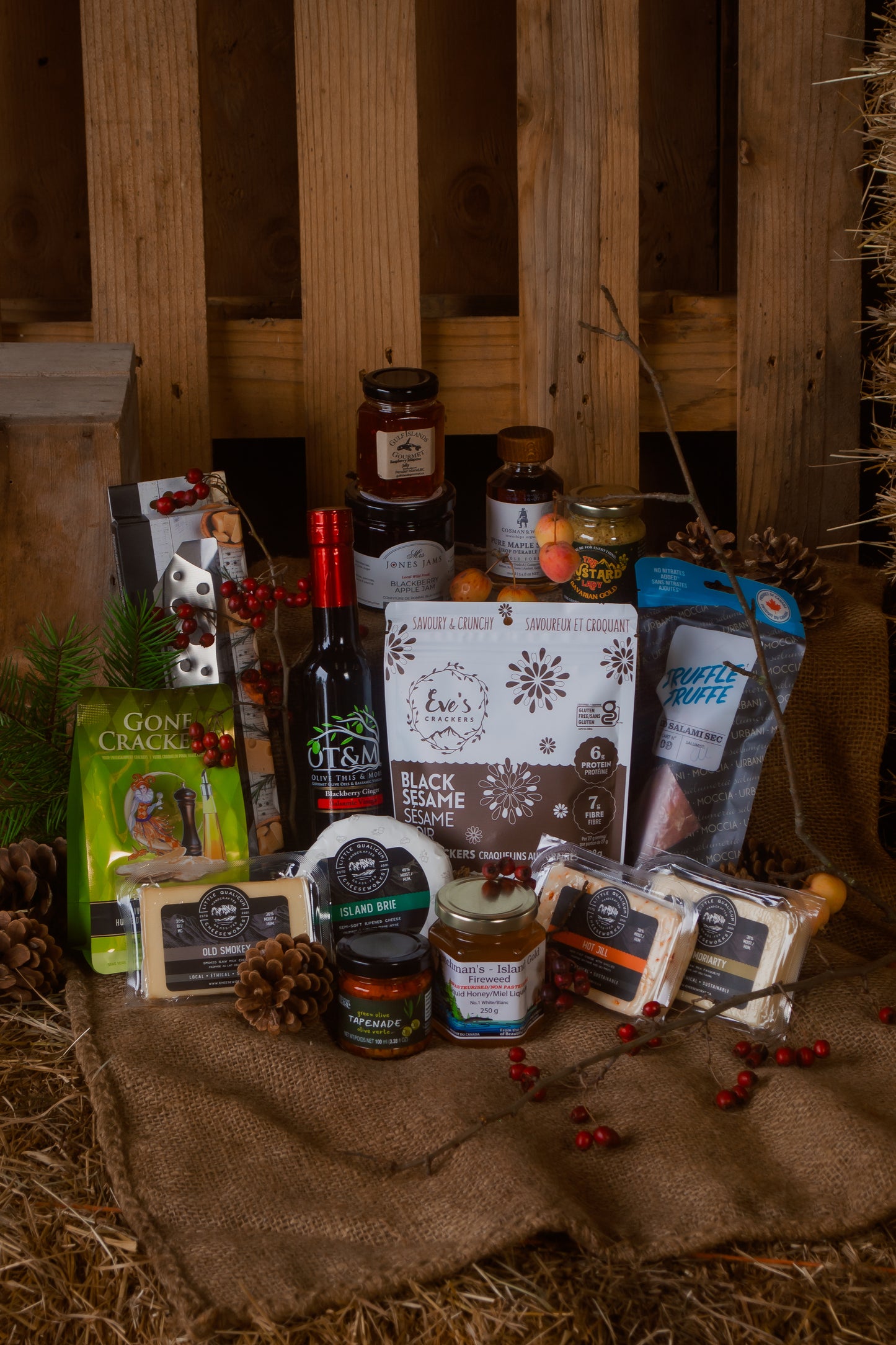 Gourmet gift basket with cheese and various Canadian food items on a rustic wooden background and Christmas decorations