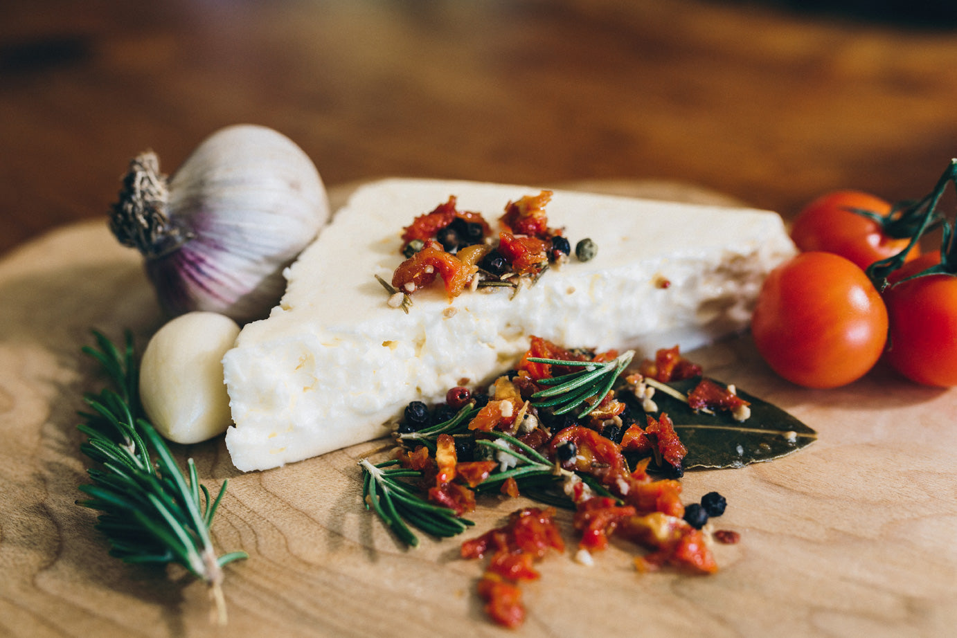 Sunshine Feta is shown with herbs and flavouring it's marinated with, including garlic, rosemary, bayleaf, peppercorns, and sundried tomato.