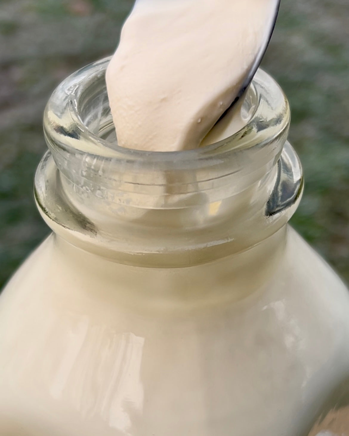 The thick cream top is scooped out of a bottle of whole milk.