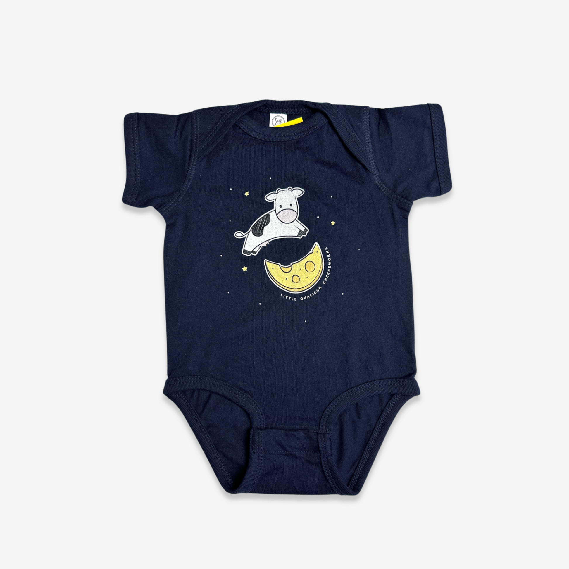 Navy blue baby onesie with a cute 6" illustration of a Holstein cow jumping over a moon made of cheese with stars in the background. Little Qualicum Cheeseworks is written around the edge of the moon.