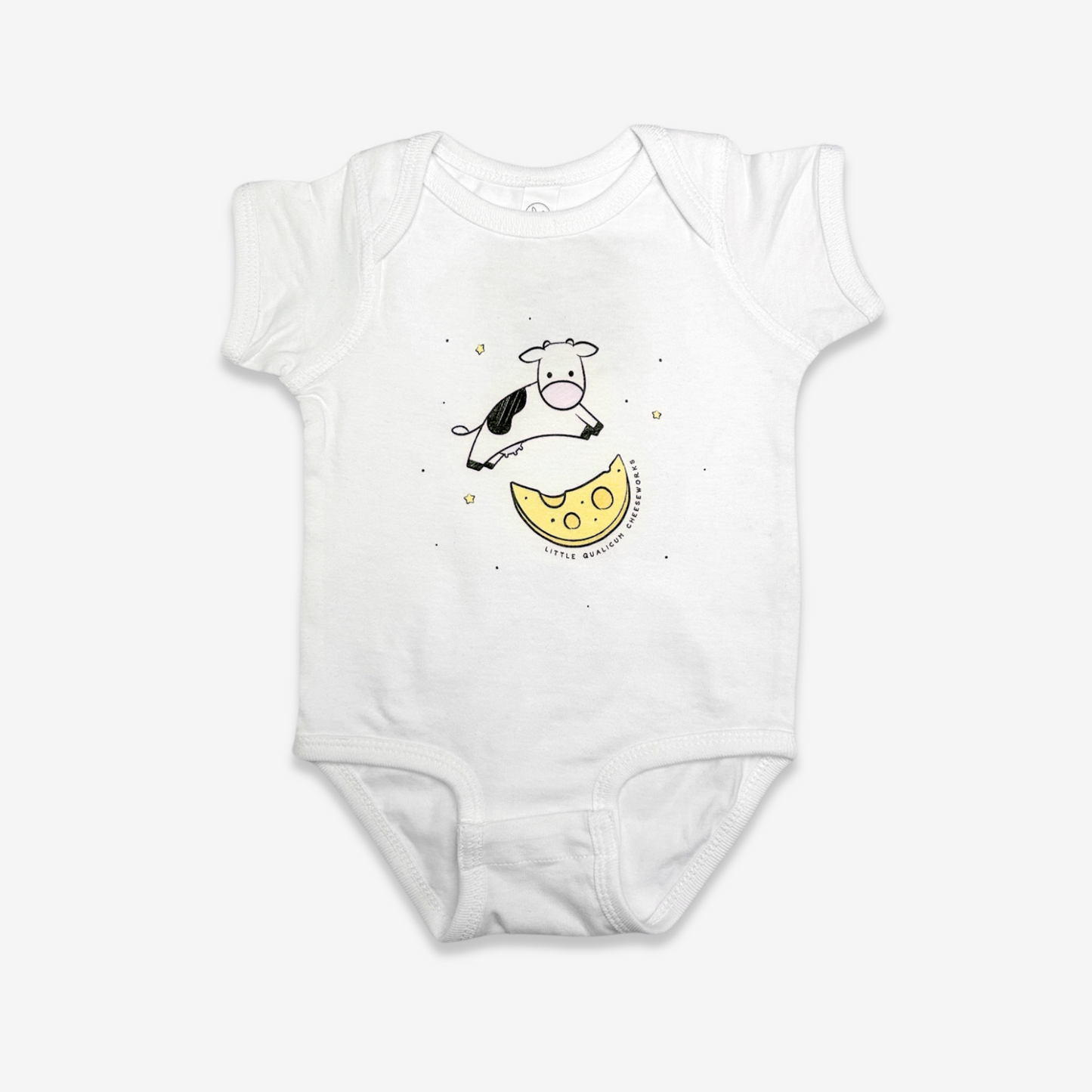 White baby onesie with a cute 6" illustration of a Holstein cow jumping over a moon made of cheese with stars in the background. Little Qualicum Cheeseworks is written around the edge of the moon.