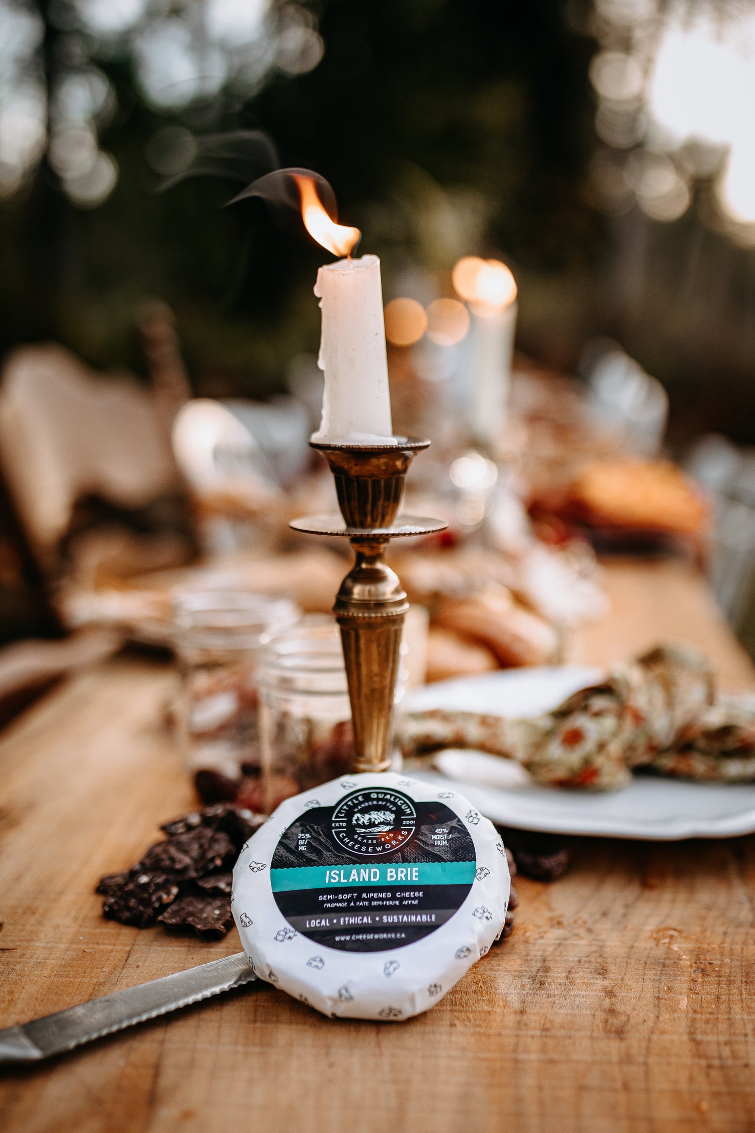 A package of Little Qualicum Cheeseworks' Island Brie sits at the end of a long dinner table set for a feast.