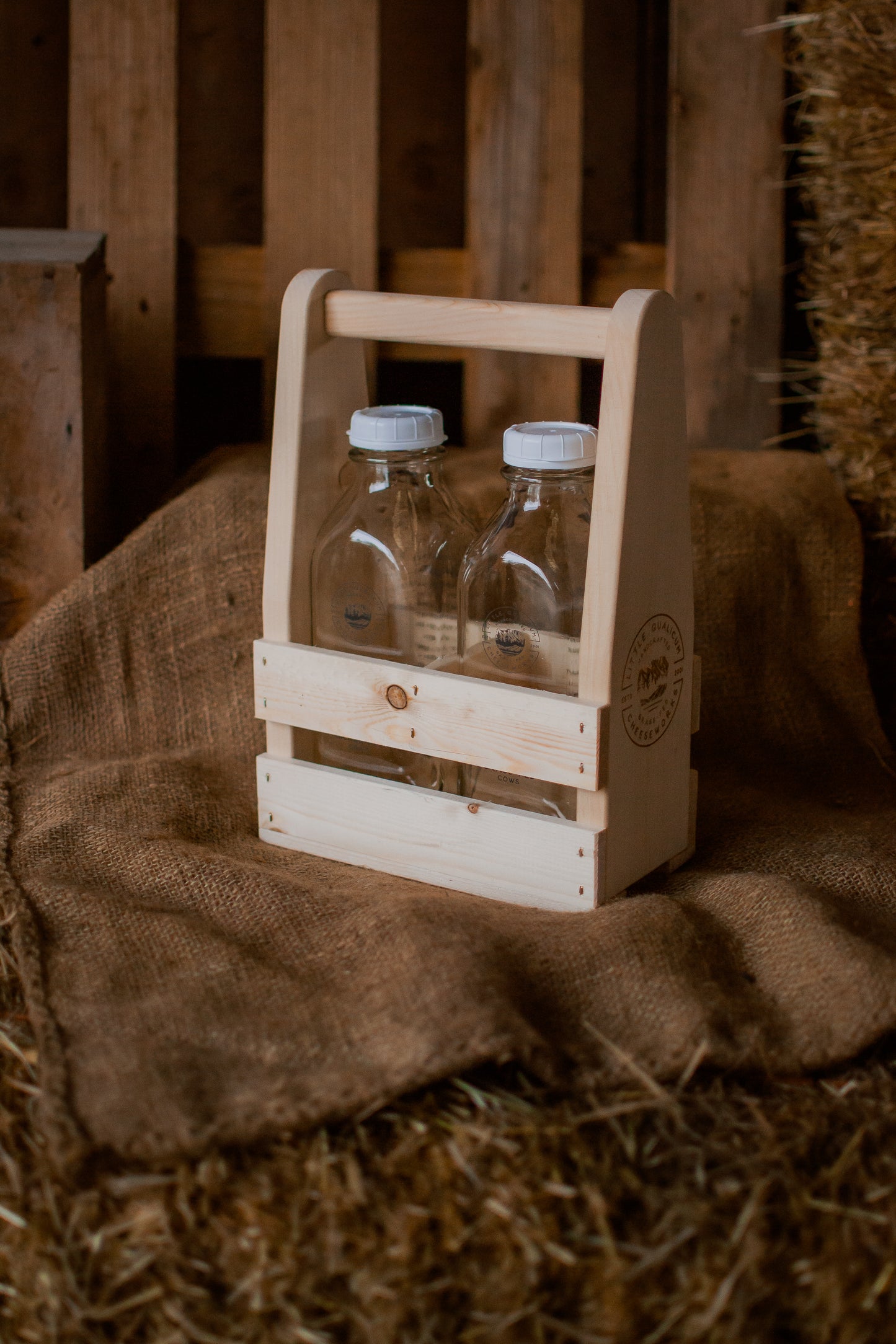 Two bottles in a small wooden carrier on a rustic background