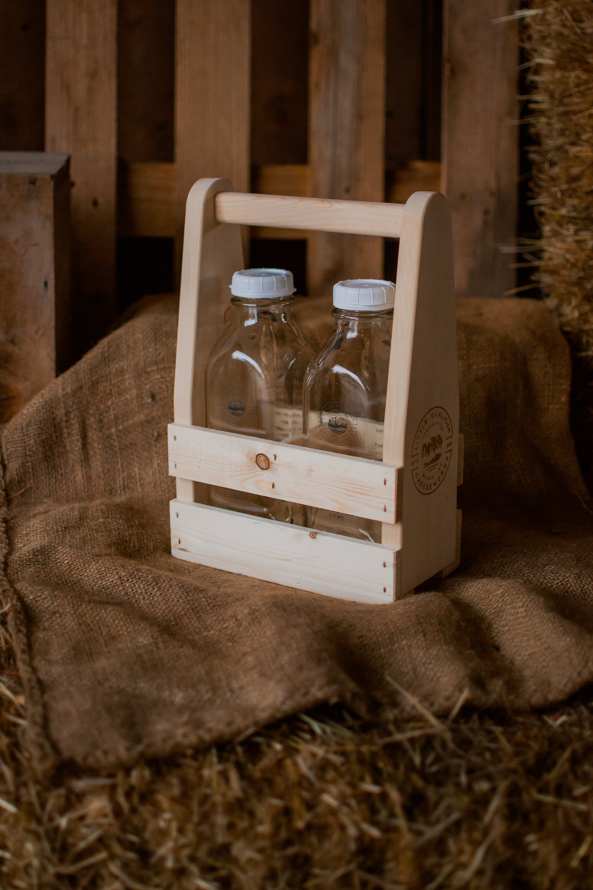 Two bottles in a small wooden carrier on a rustic background