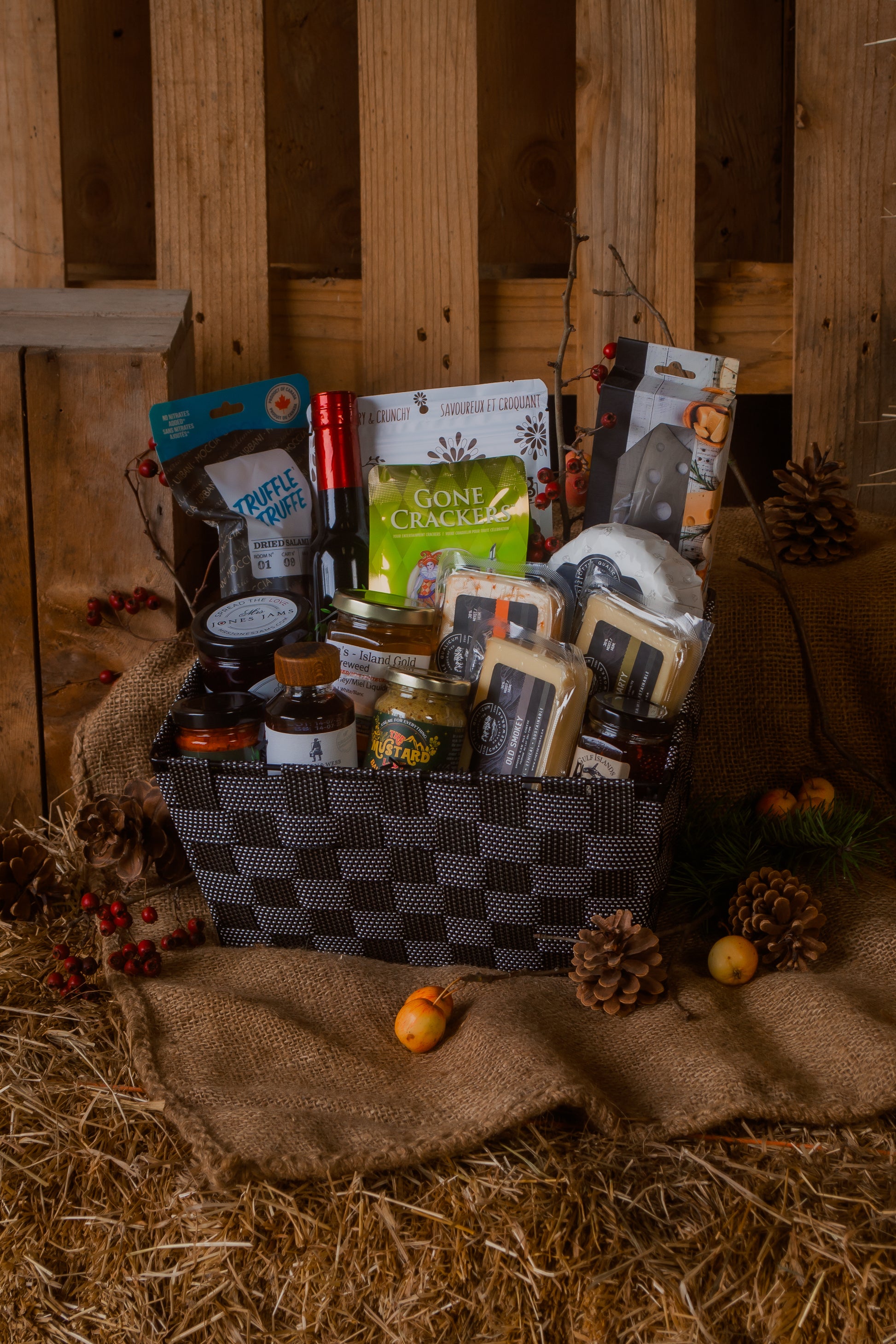 Gourmet gift basket with cheese and various Canadian food items on a rustic wooden background