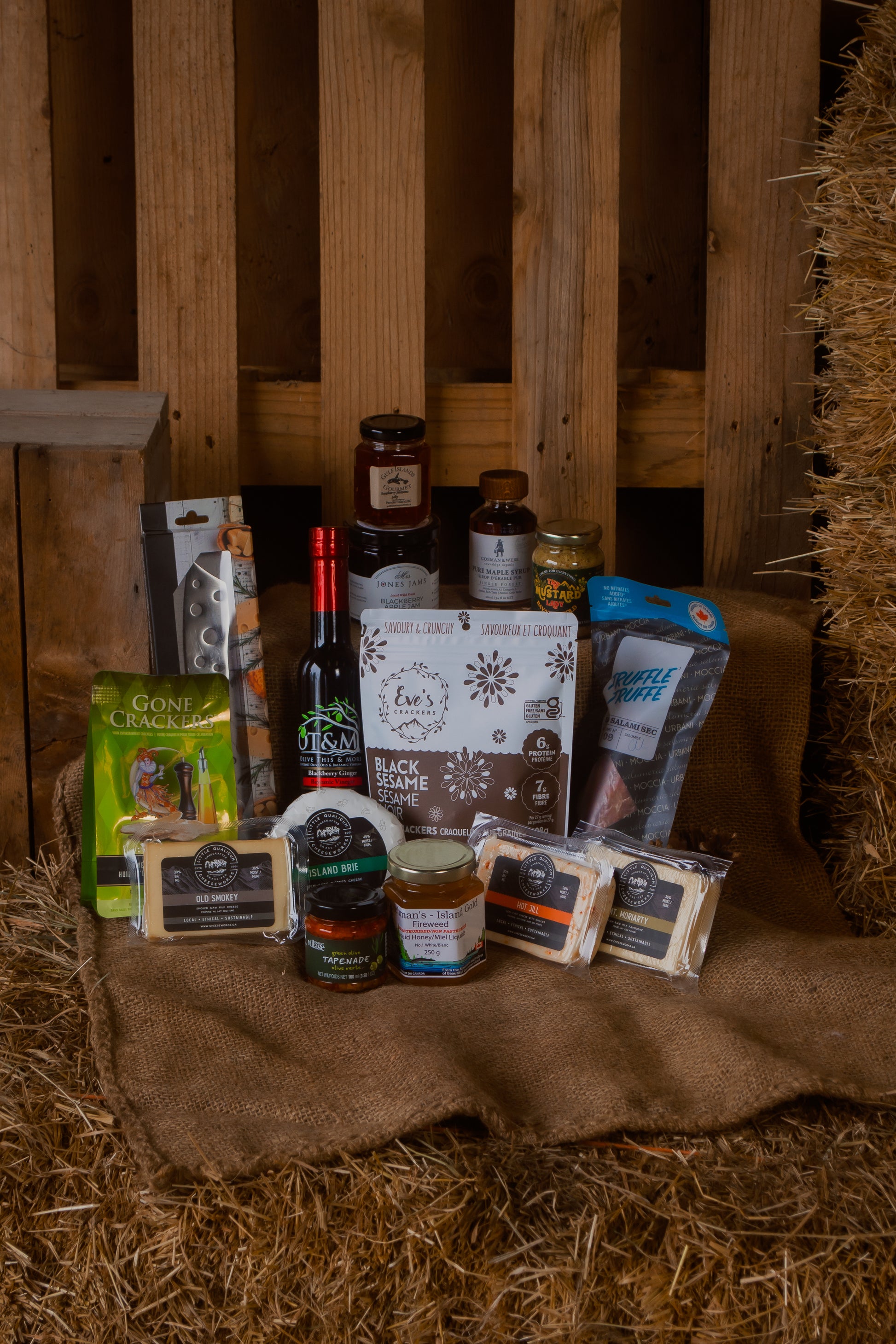Gourmet gift basket with cheese and various Canadian food items on a rustic wooden background