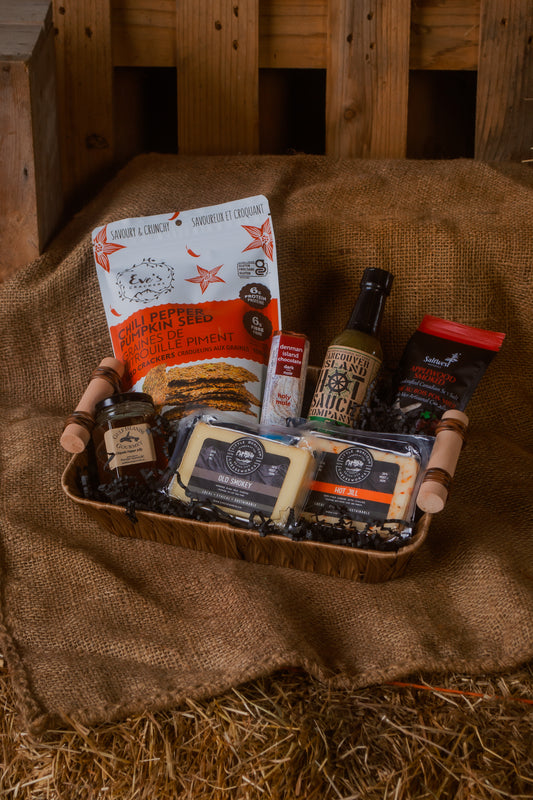 Assorted BC local food items in a gift basket, against a rustic wooden background.