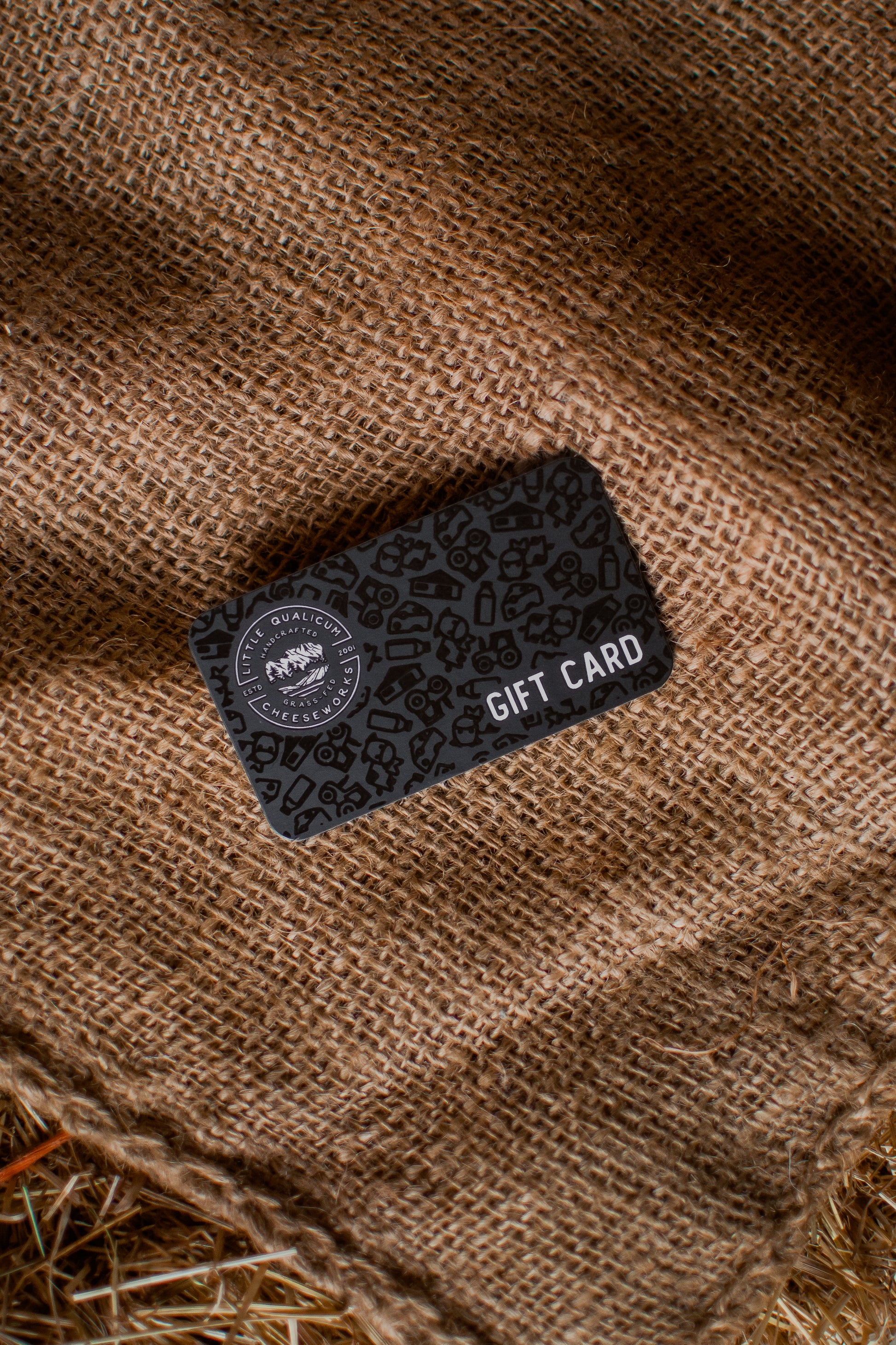 Black gift card with a logo on a brown textured surface
