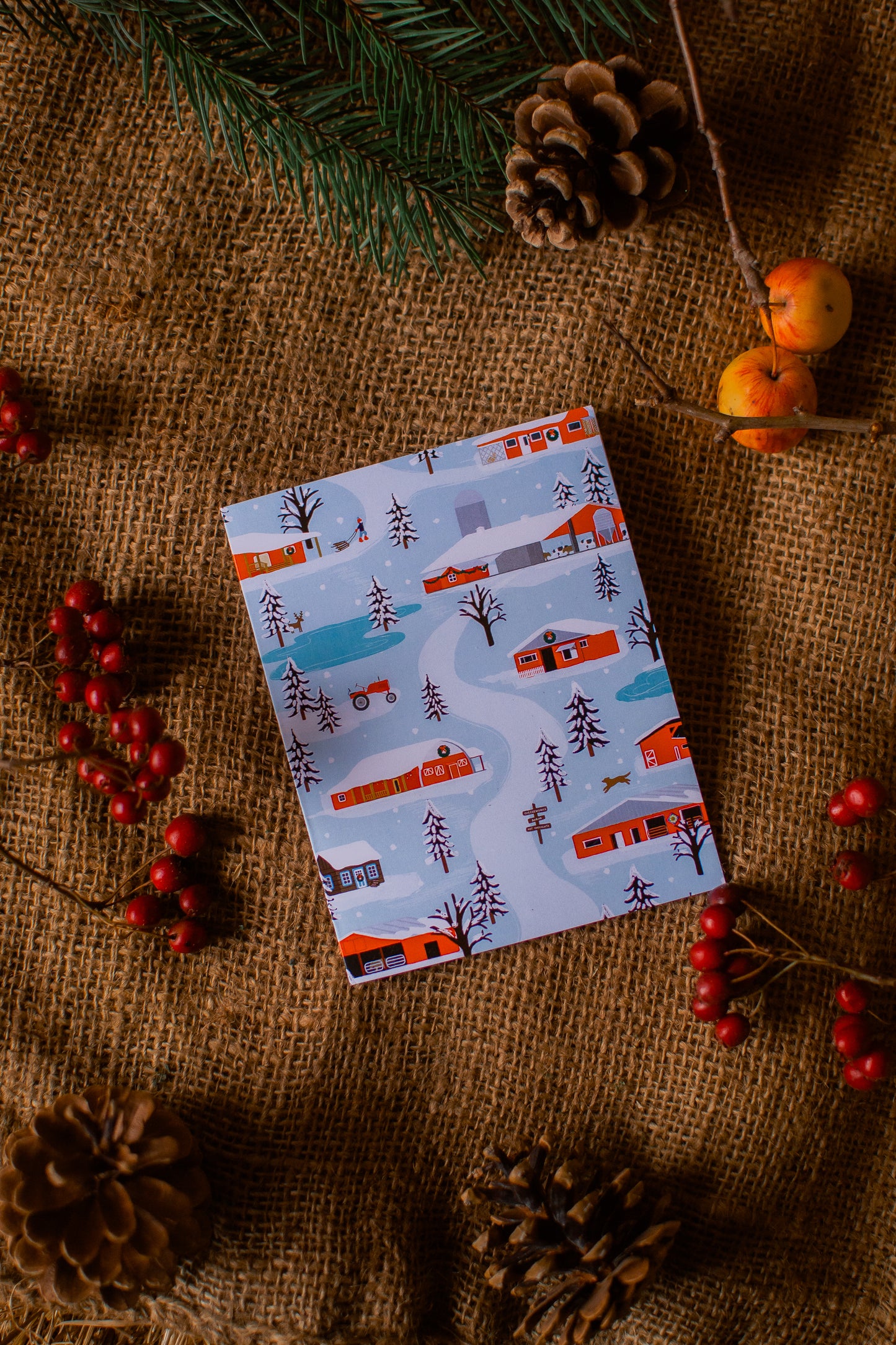 Christmas card with winter scene design on a rustic background with pine cones and berries