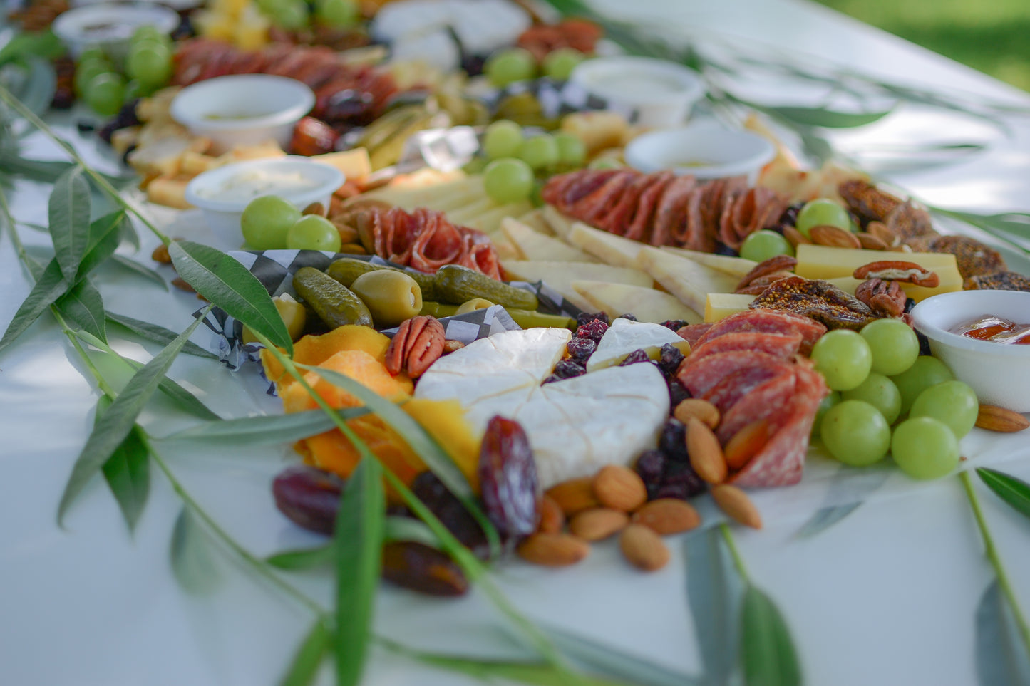 Closeup of graze table, cheese is arranged with meats, fresh fruit, and nuts