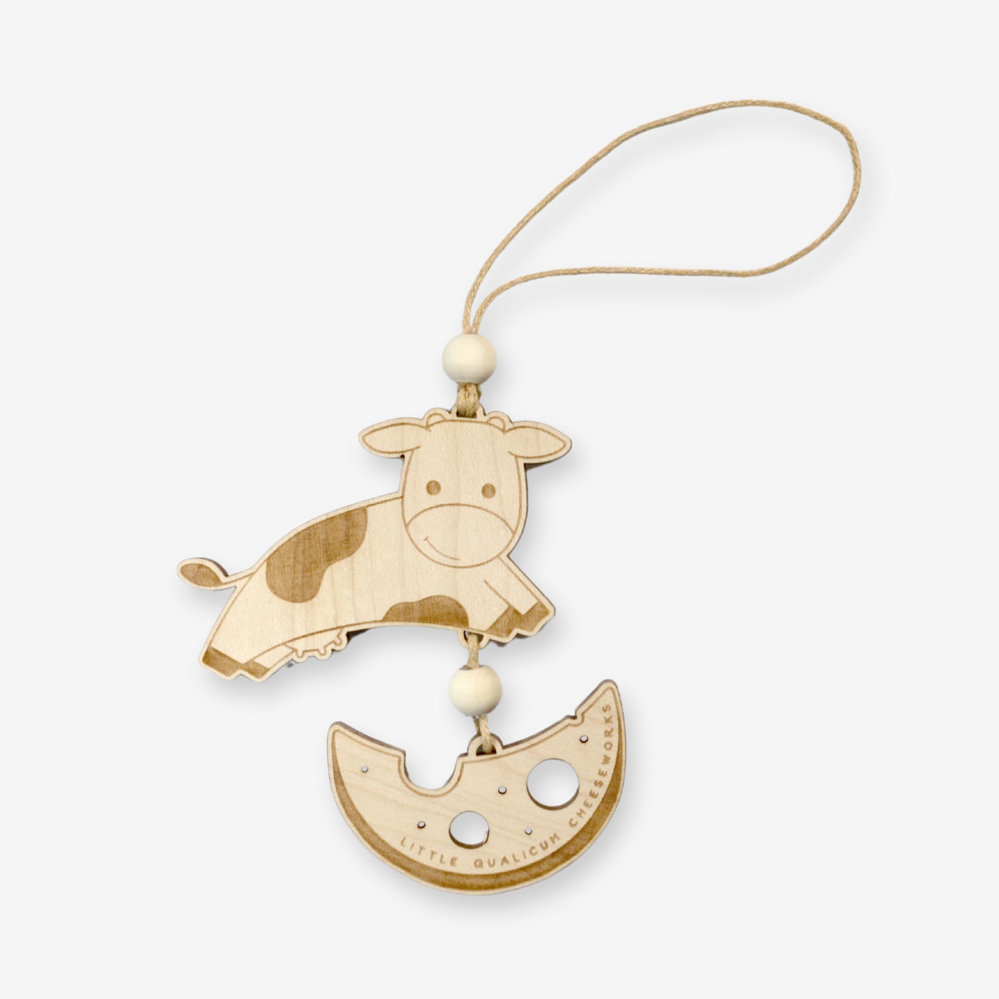 Made of wood, a cute cow jumps over a cheese moon. The moon is attached from under the cow with with string so the cow appears to be jumping over it. Details are mostly engraved, with the exception of the holes in the cheese moon, which are cut out. A wood bead conceals knots in the string above and below the cow. The string matches the natural wood tones in the rest of the ornament.