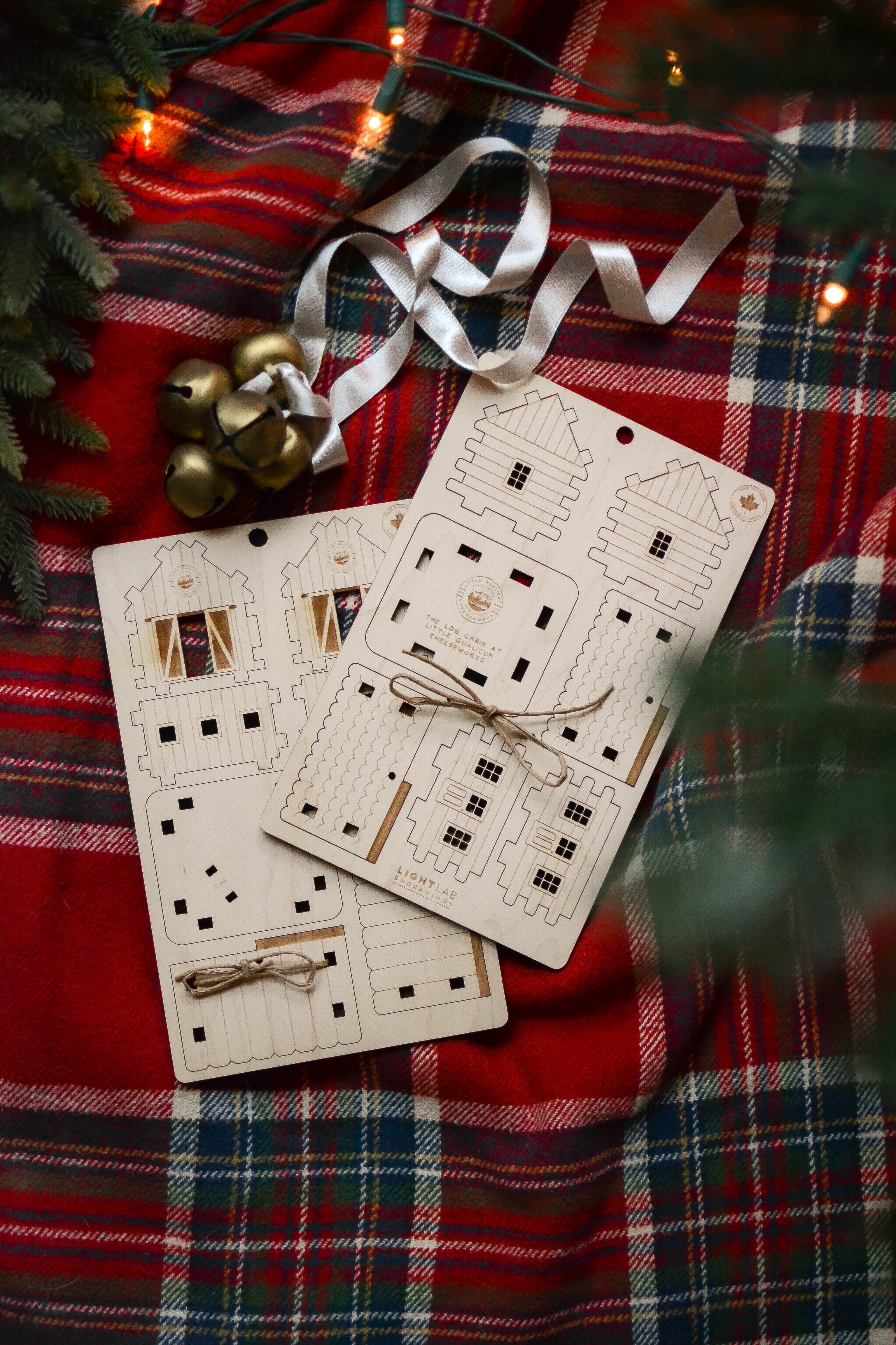 The unassembled barn and cabin ornaments are styled under a Christmas tree.