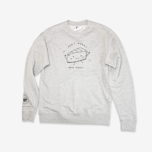 The artwork on the grey heather sweatshirt is printed in a contrasting black. The sweatshirt has long sleeves. At the lower end of the left sleeve near the cuff, the LQC logo is printed with "Vancouver Island" written below. On the front of the sweatshirt is an 8" line drawing of a personified wedge of Brie. The Brie dances with little arms in the air and smiles. The text  "Don't worry, Brie happy" is written around the illustration.