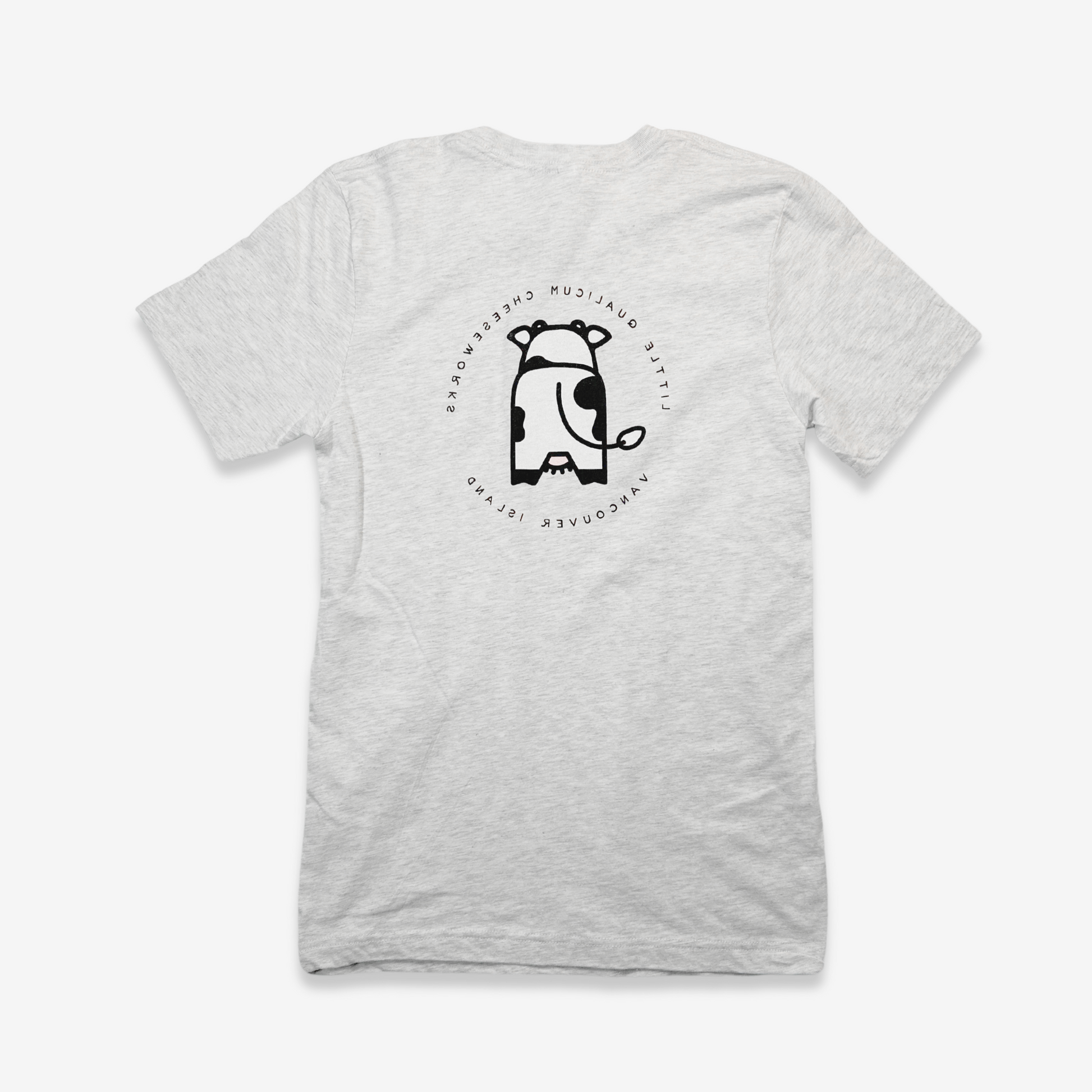 The back of the shirt shows a simplified cute 8" illustration of a Holstein dairy cow from the back. The text "Little Qualicum Cheeseworks Vancouver Island" is written in a circle around the cow, but mirrored.