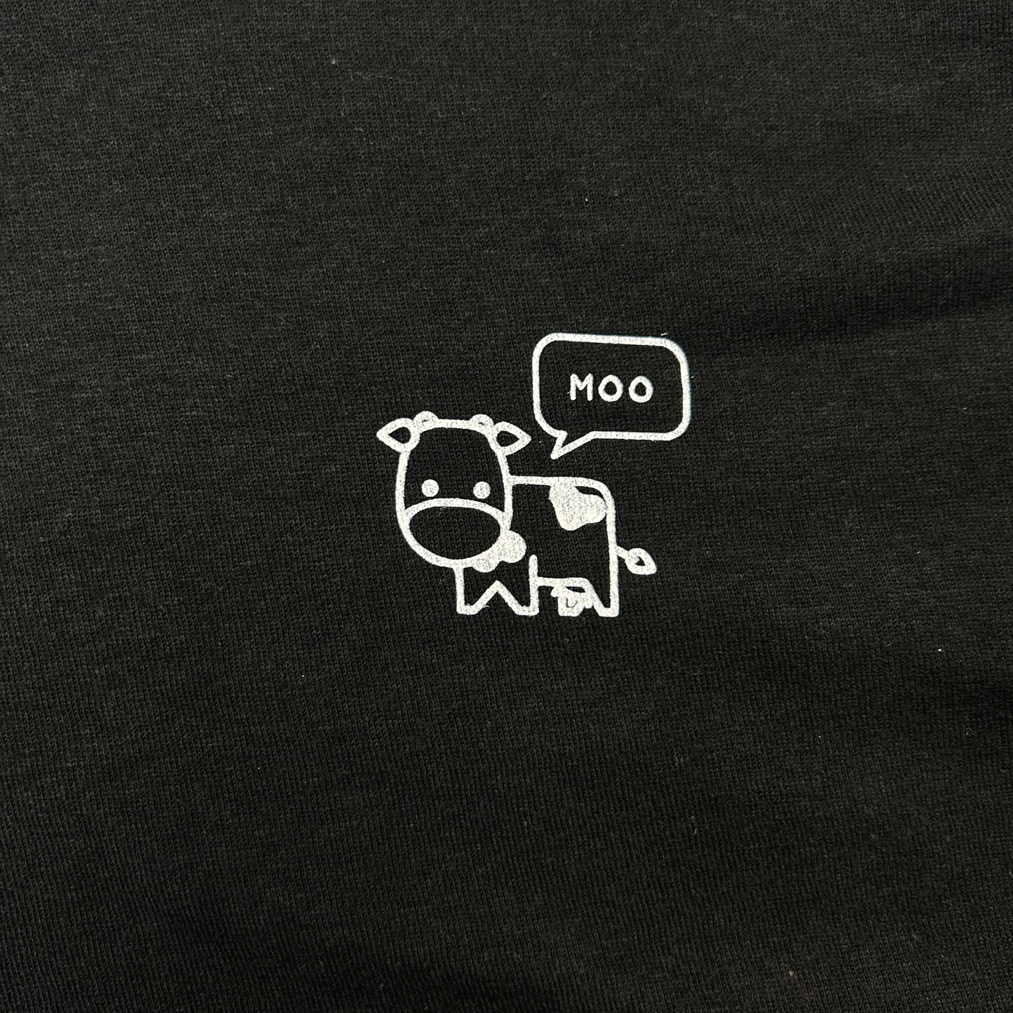 Closeup of pocket print shows a line drawing of a cow with a speech bubble containing the word "Moo".